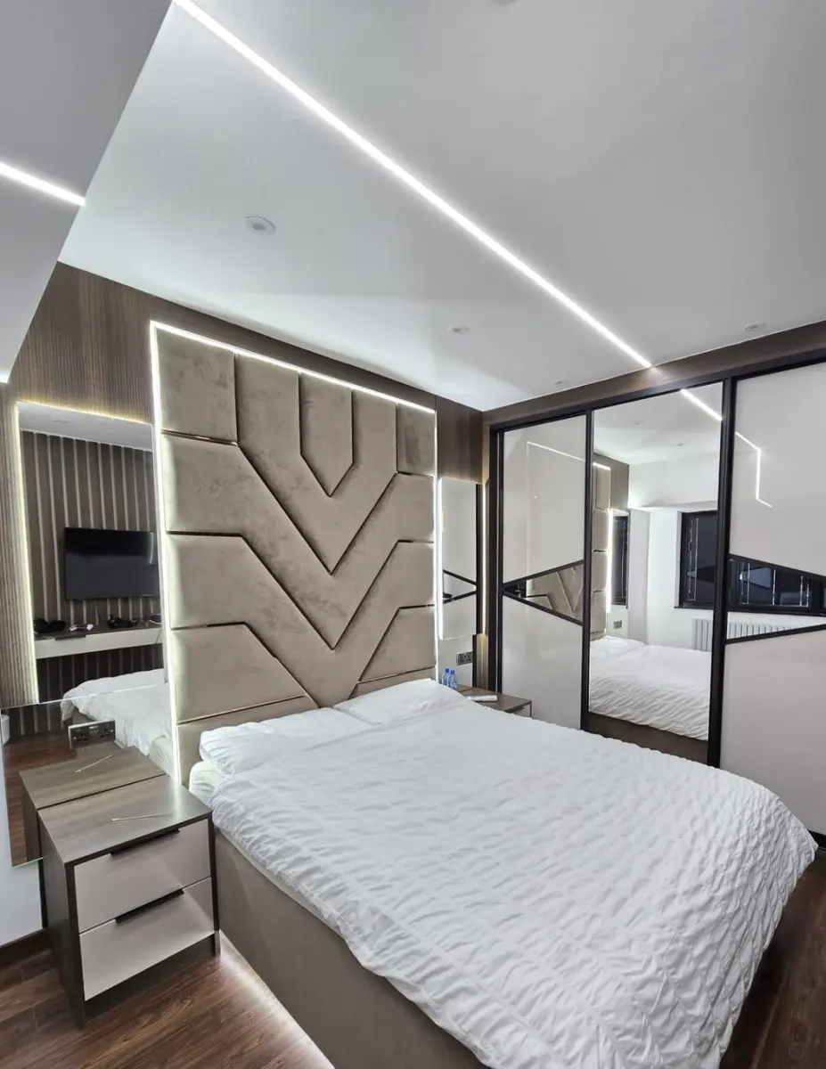 Complete bedroom with upholstered geometric feature wall and mirrored wardrobes